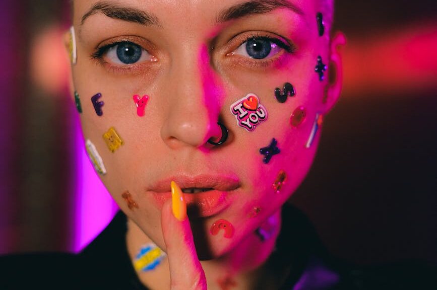 bald woman with stickers on face showing shush sign