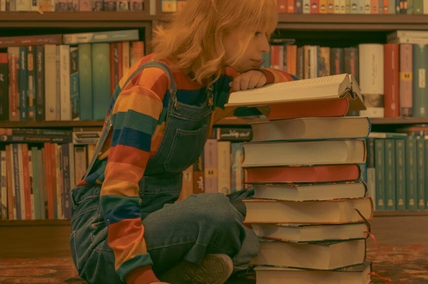 young woman reading a book while sitting on the floor in a library