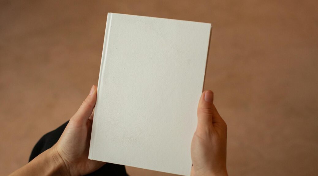 person holding hardcover book with blank cover