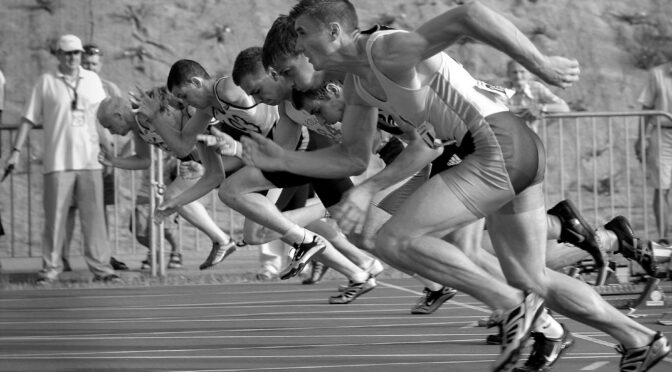 athletes running on track and field oval in grayscale photography