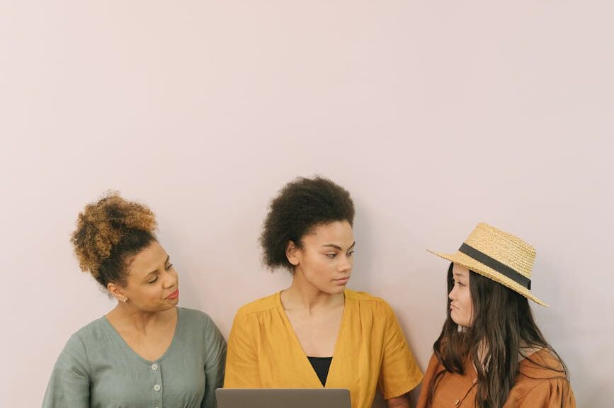 a woman in yellow dress holding a laptop while talking to her colleagues