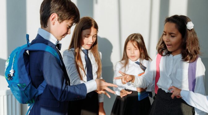 children in school uniform playing rock paper scissors